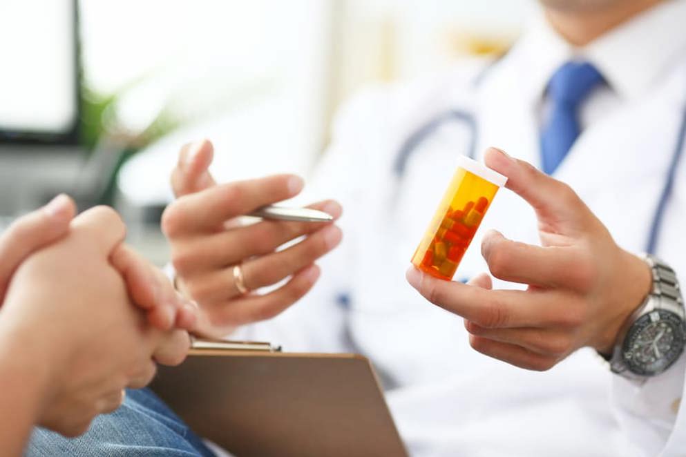 Close-up of doctor's hand holding medicine and giving it to his patient.